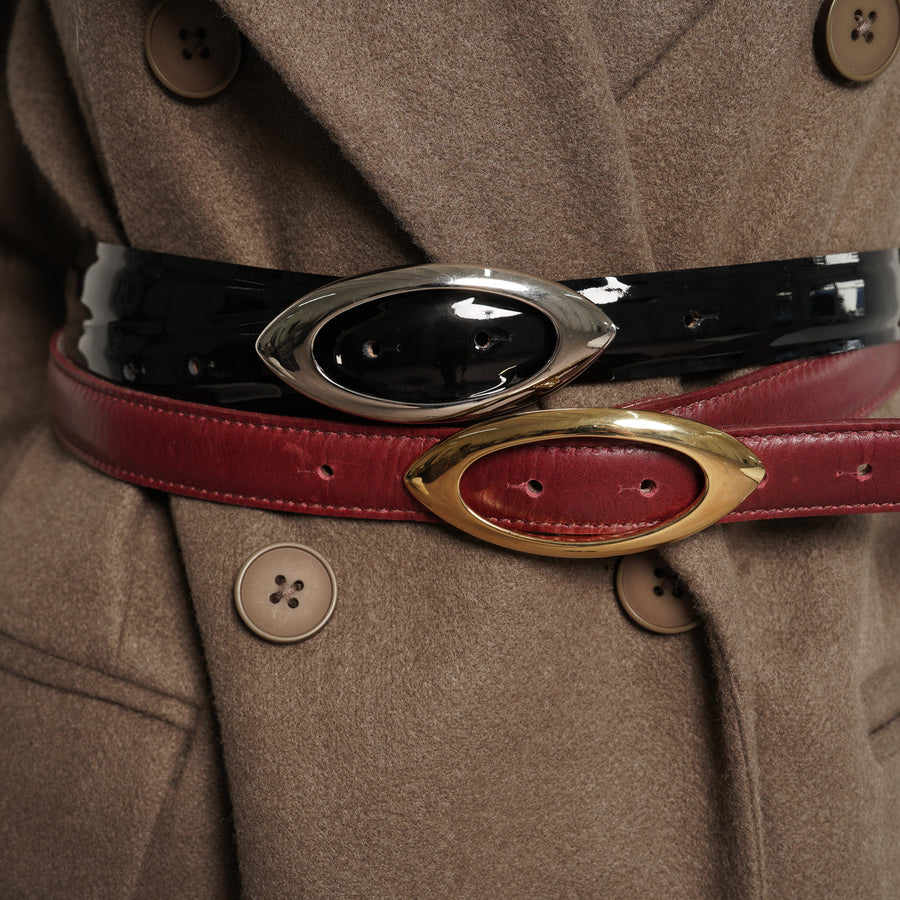 Close-up of a coat with a red belt featuring gold buckle and black belt with silver buckle - Streets Ahead