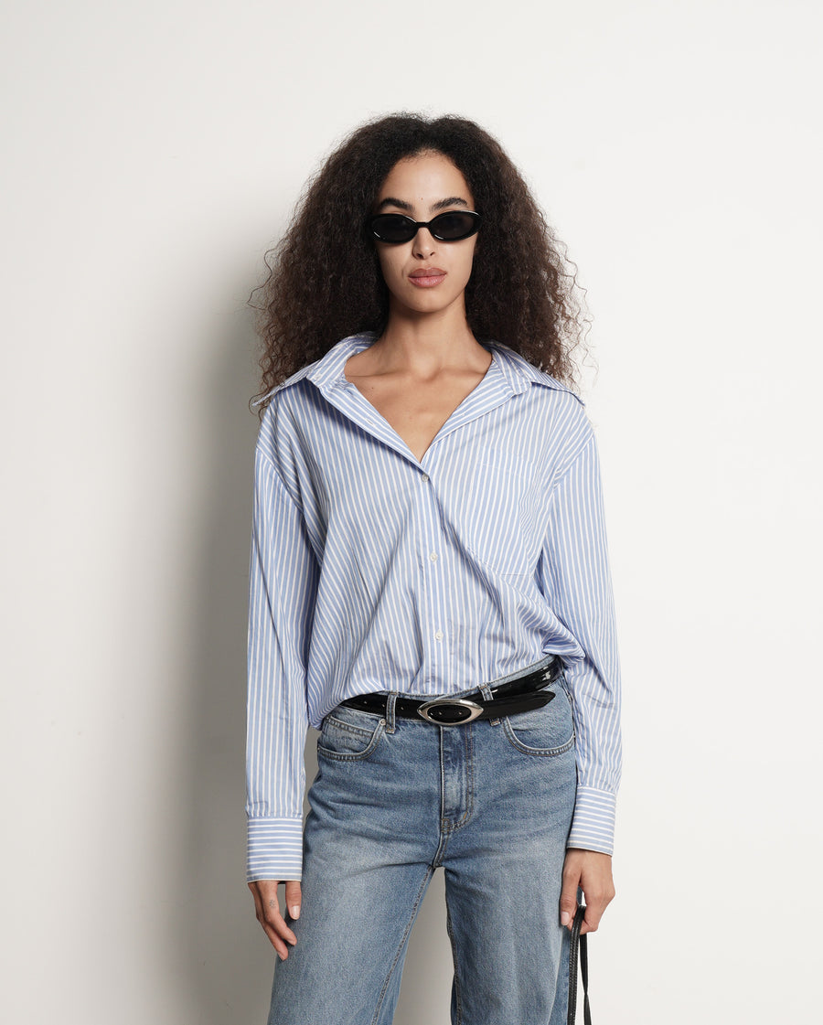 Person wearing a blue and white striped shirt and jeans with a black patent leather belt - Streets Ahead