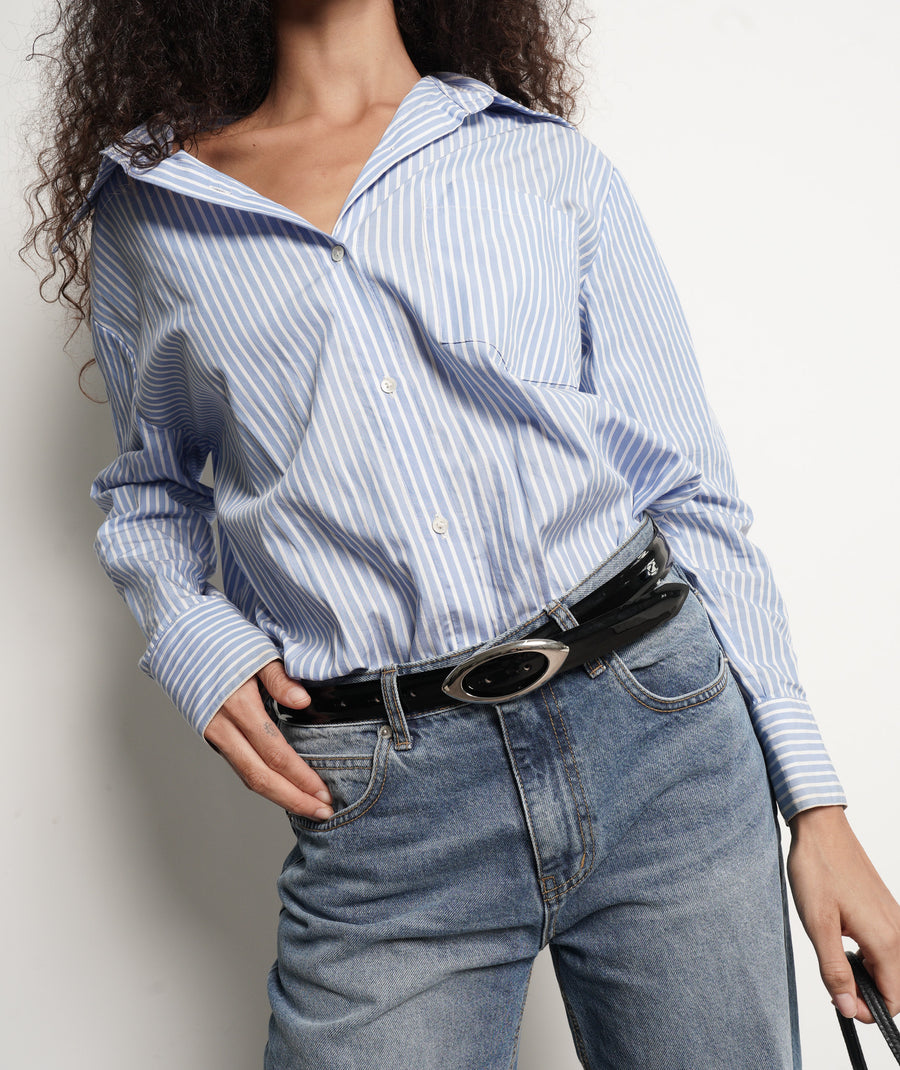 Person wearing a blue and white striped shirt and jeans with a black patent leather belt - Streets Ahead