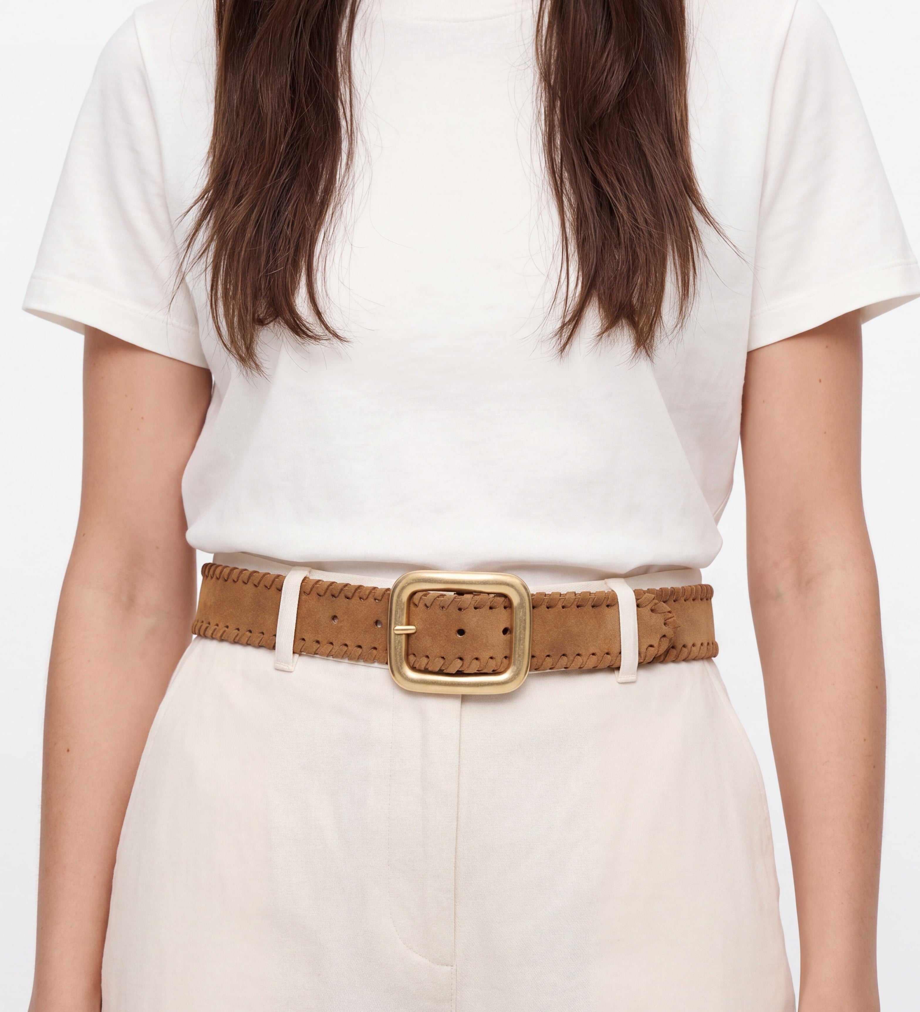 Person wearing a white t-shirt and beige pants with a brown belt on a plain background