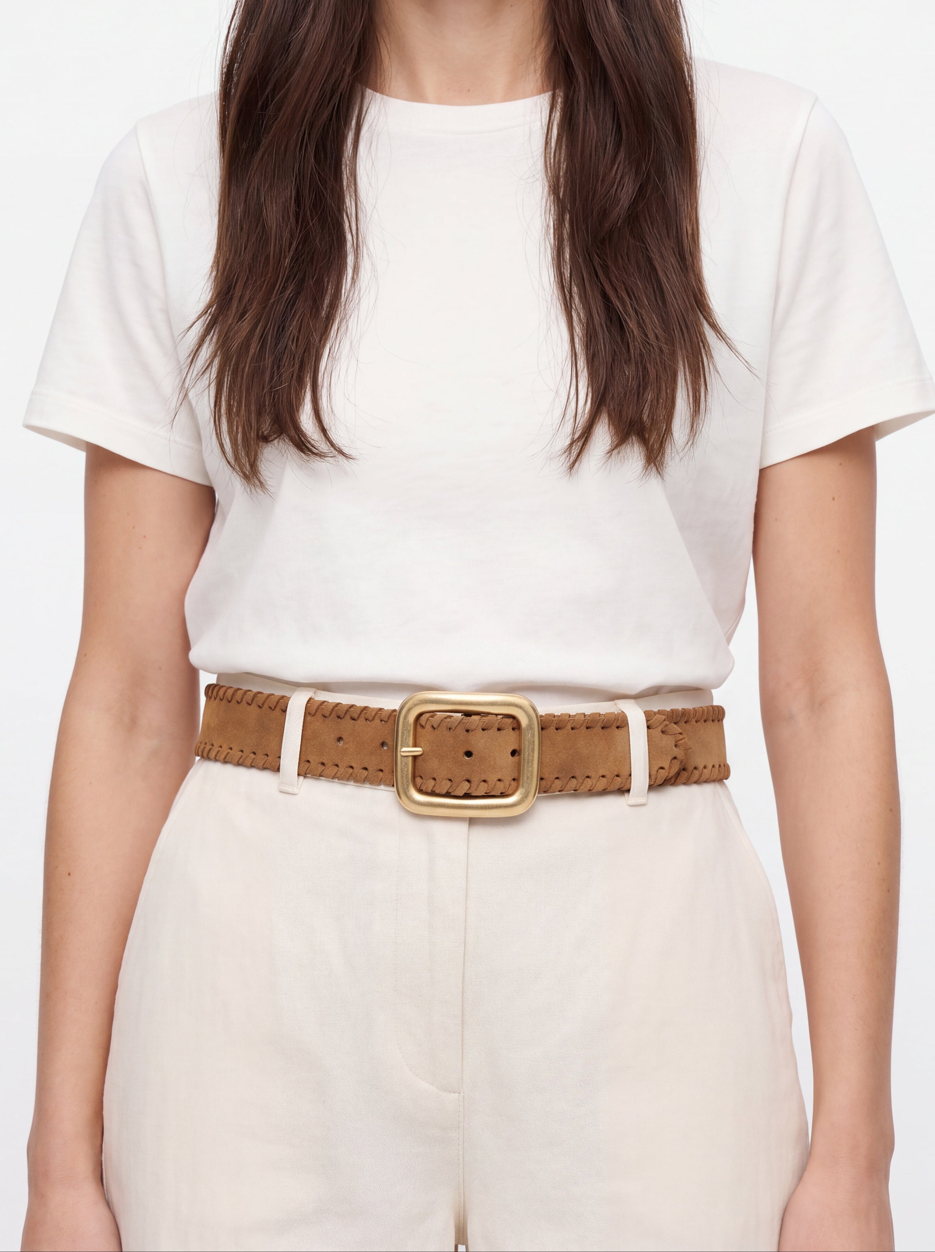 Person wearing a white t-shirt and beige pants with a brown belt on a plain background