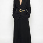 Woman wearing a long black blazer dress with a belt on a white background