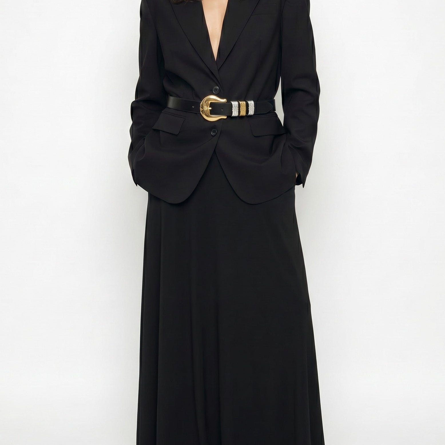 Woman wearing a long black blazer dress with a belt on a white background