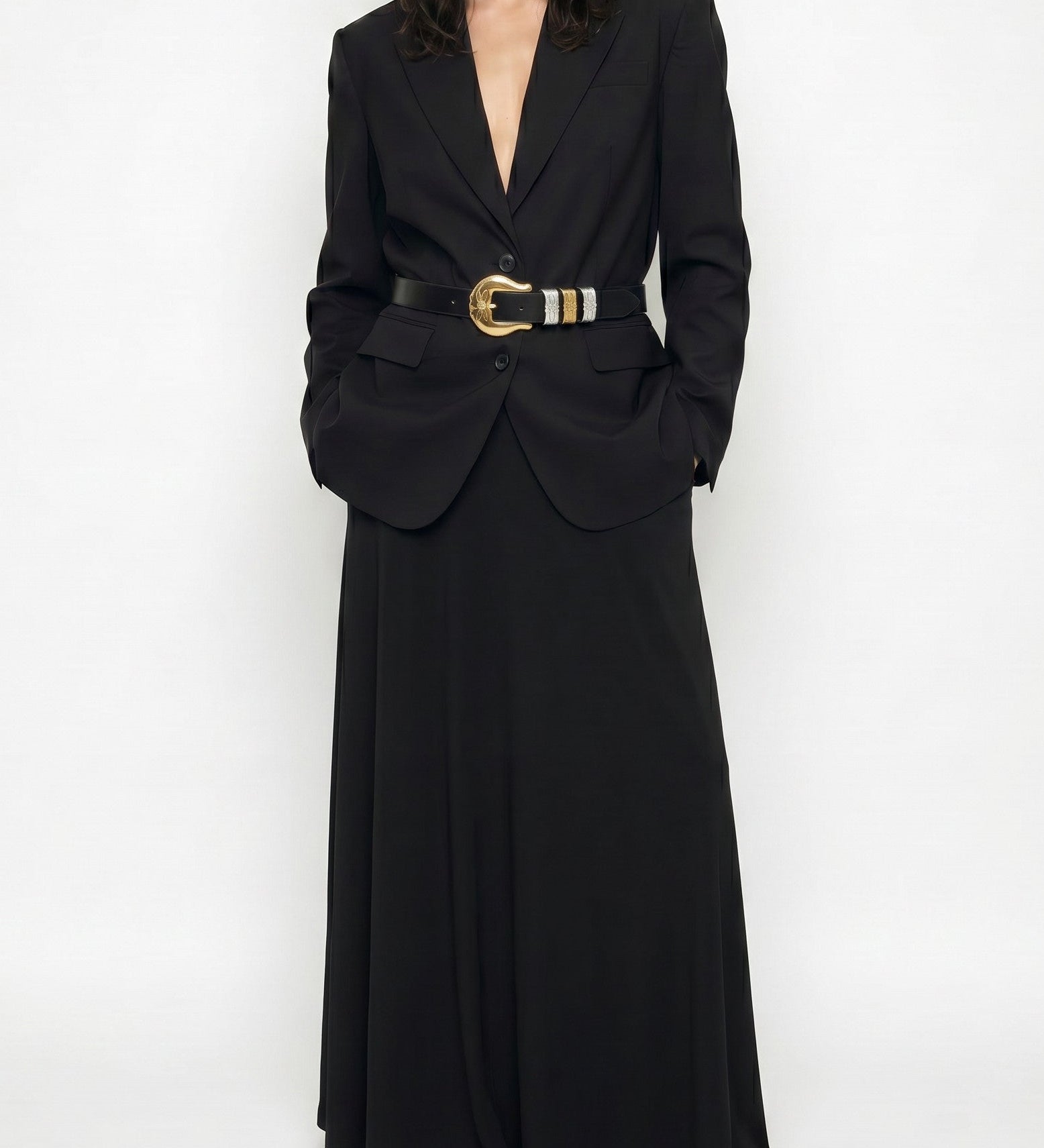 Woman wearing a long black blazer dress with a belt on a white background
