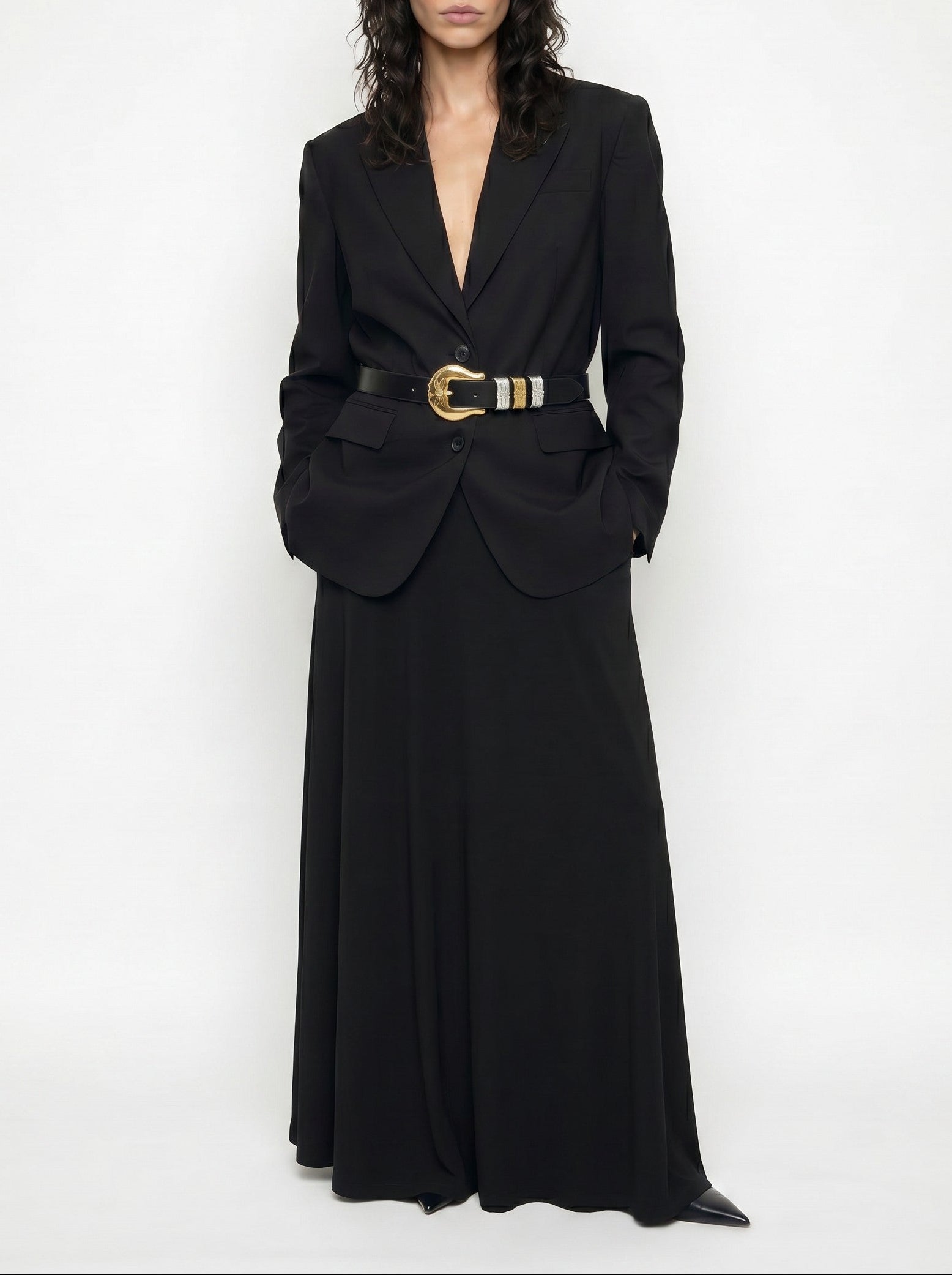Woman wearing a long black blazer dress with a belt on a white background