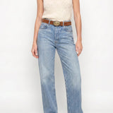 Woman wearing a sleeveless top and jeans on a white background