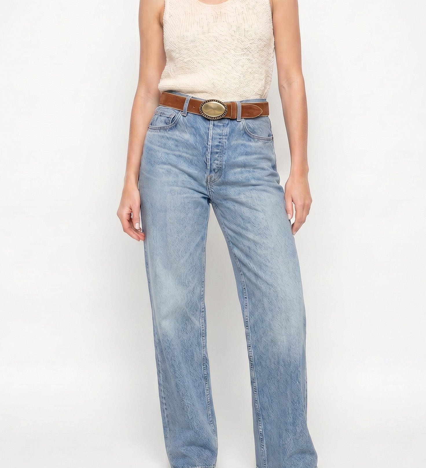 Woman wearing a sleeveless top and jeans on a white background