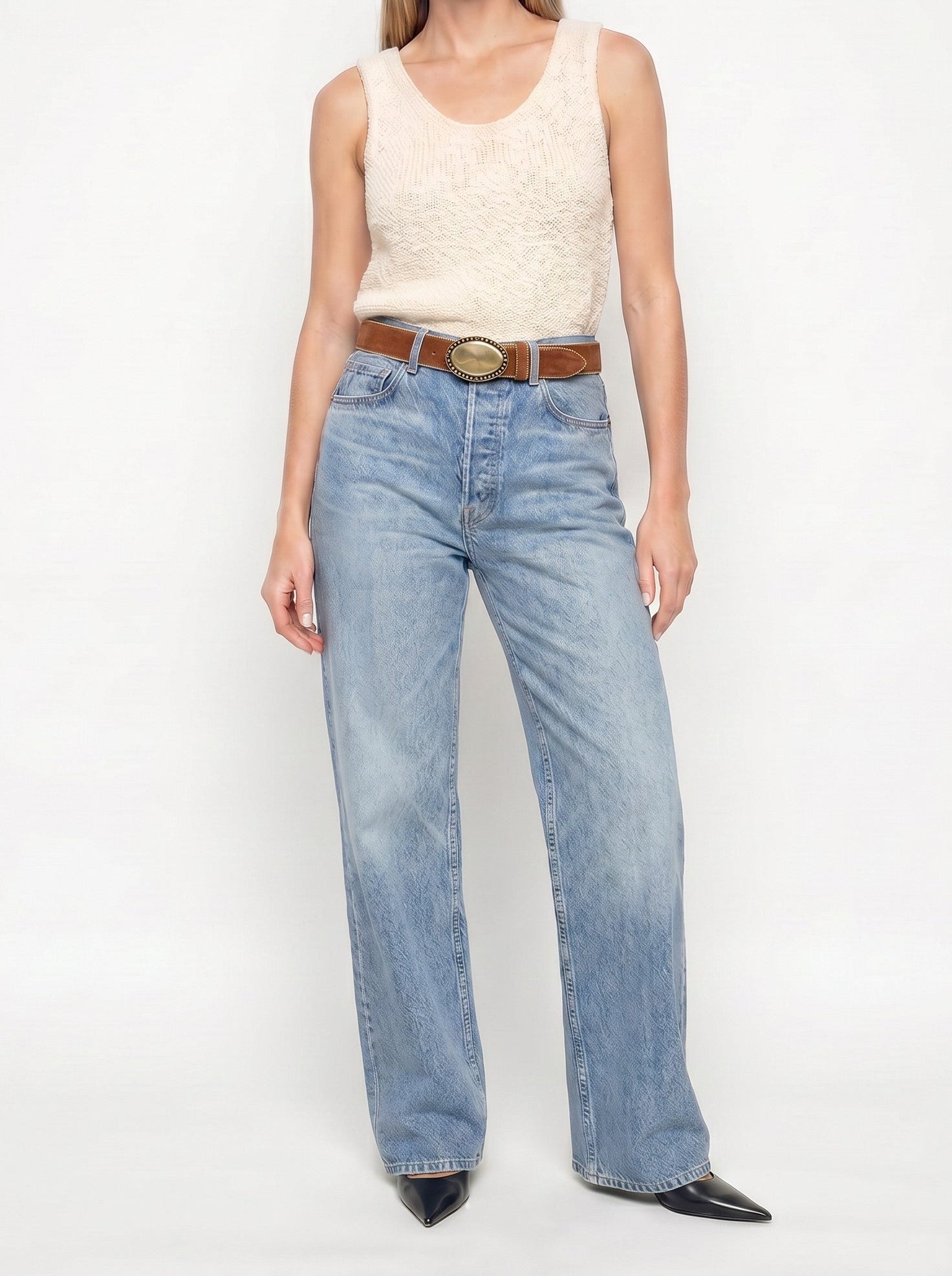 Woman wearing a sleeveless top and jeans on a white background