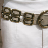 Close up of the Saskia Belt brass buckle and oval brass hardware woven through shimmer ivory leather